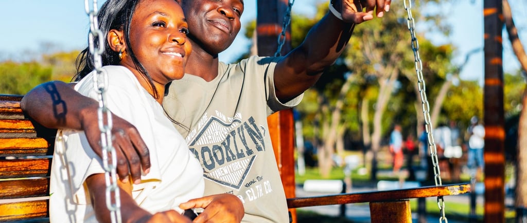 a romantic couple sitting together on a bench at the park