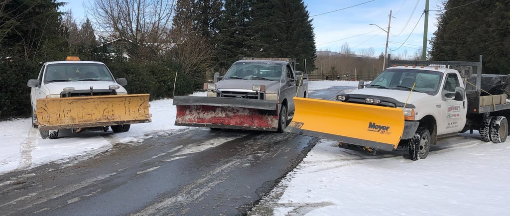3 trucks with snow plows on the front parked