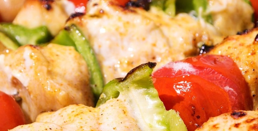 Close-up of grilled chicken skewers with bell peppers and tomatoes.