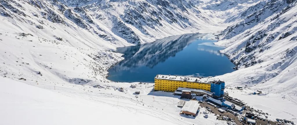 a large laguna del inca surrounded by mountains and snow portillo chile