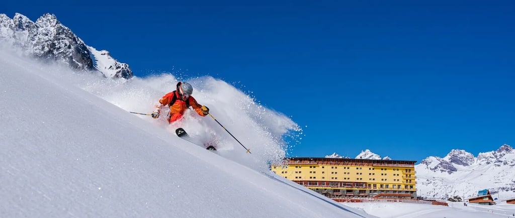 a person skiing down a snowy mountain slope in portillo chile