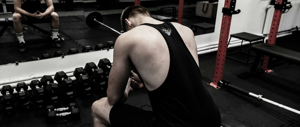Atleta de musculação descansando após treino intenso para evitar overtraining