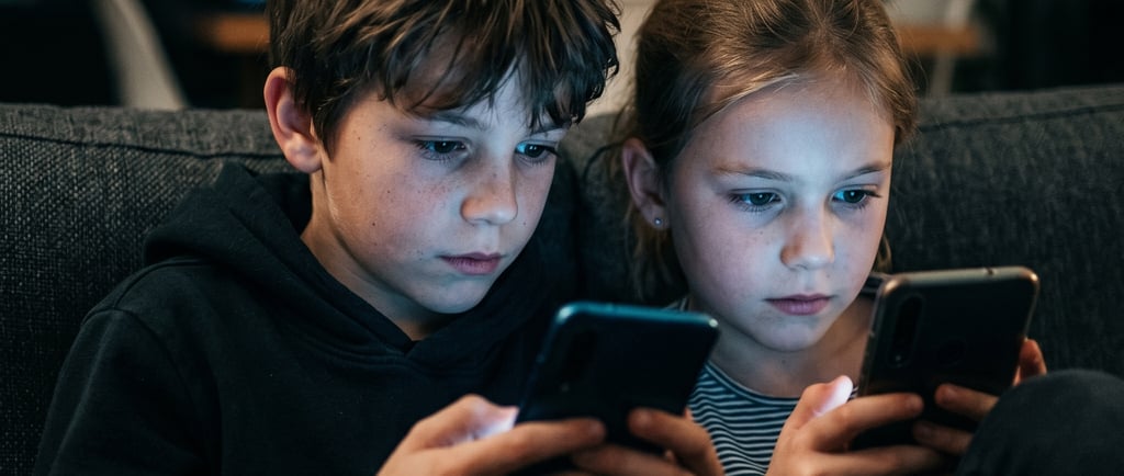 Niños usando teléfonos móviles en casa durante la noche mientras miran la pantalla de sus smartphone