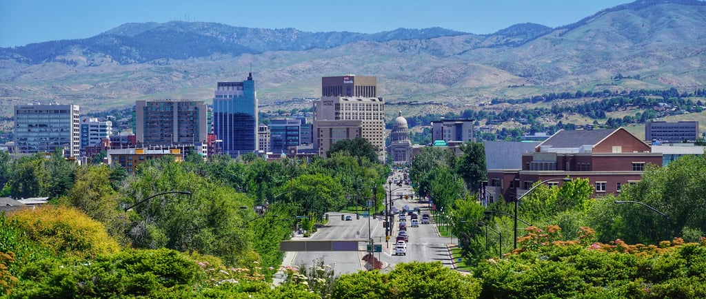Panoramic Boise skyline view featuring the Idaho State Capitol building and foothills under a clear blue sky.