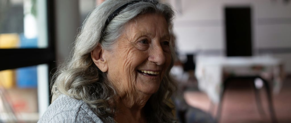 Smiling elderly woman with wavy grey hair laughing during a social gathering