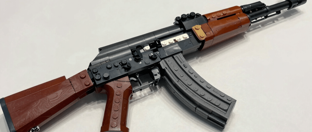 Detailed replica of an AK-47 rifle made from toy building blocks on a white table.