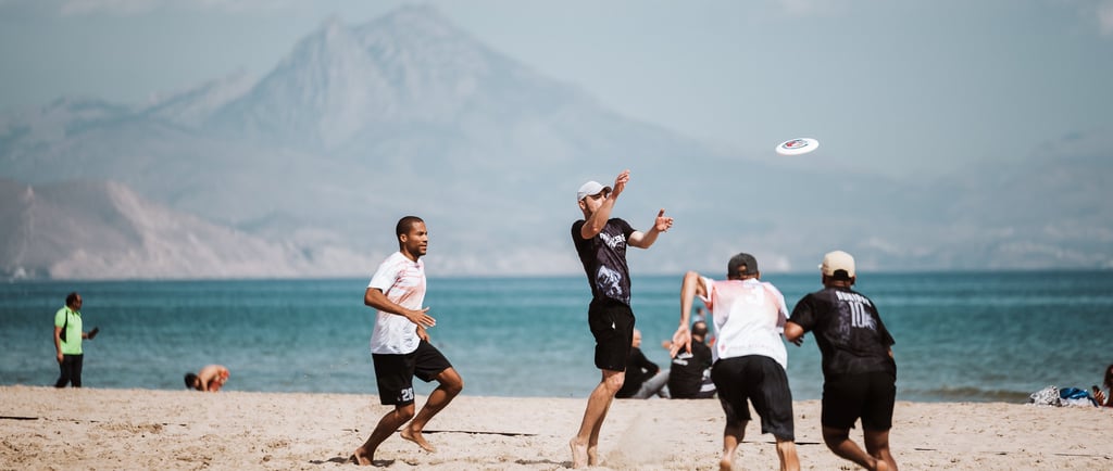a group of people playing ultimate frisbee on a beach