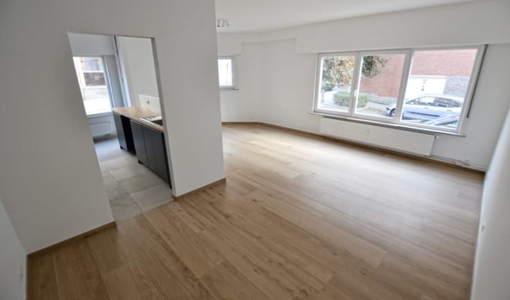 a room with a wooden floor and a kitchen