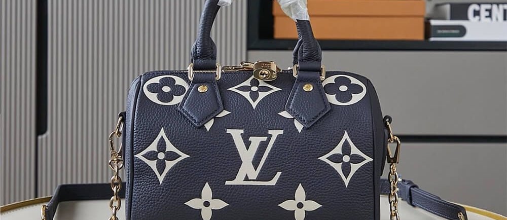 Navy blue Louis Vuitton Speedy Bandouliere bag with white giant monogram print and gold chain strap.