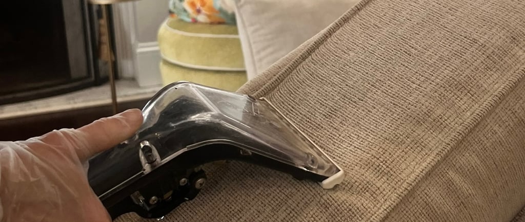 Professional upholstery cleaning technician using steam extraction tool on beige sofa fabric in Denv