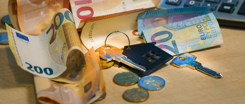 House keys on Euro banknotes and coins with a calculator for mortgage and real estate financing.