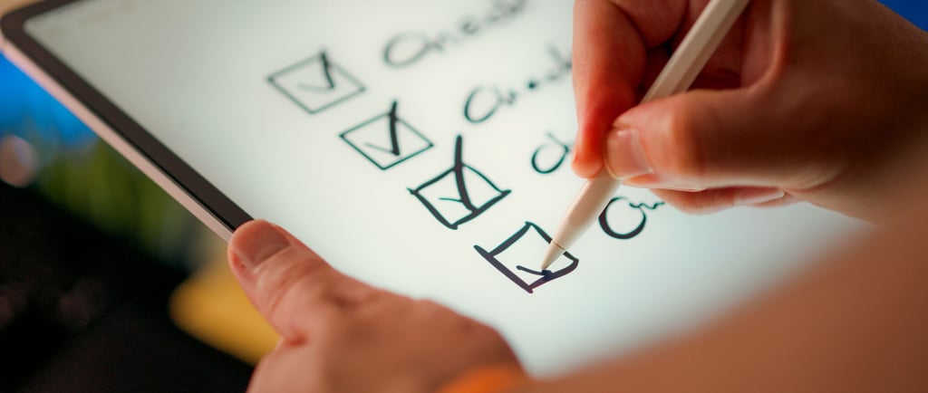 Hand using a white stylus to mark a digital checklist on a tablet screen for task management.