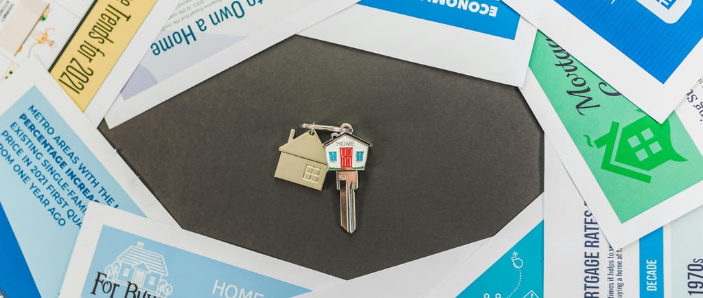 House keys on a keychain centered among real estate market reports and home buying guides.