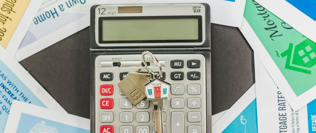 House keys on a digital calculator surrounded by mortgage and home buying financial documents.