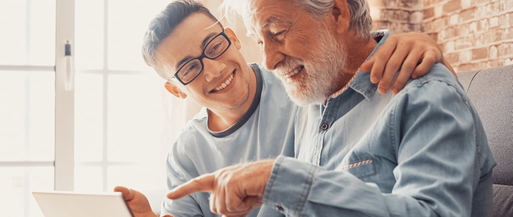 a young man helping an elderly man with a laptop