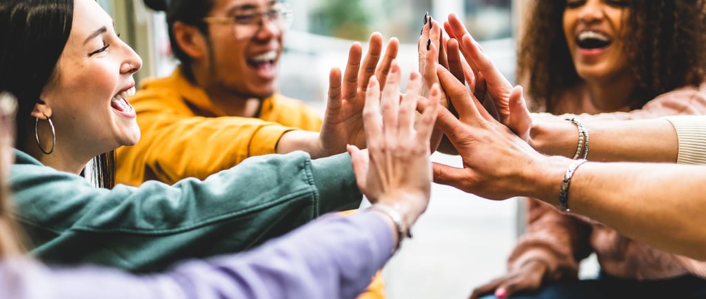 a group of people sitting around a table with their hands together