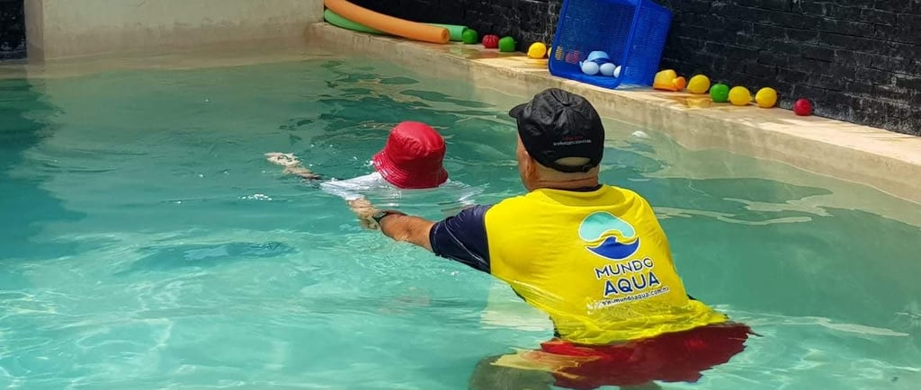 a man in a yellow shirt is playing with a ball in the water