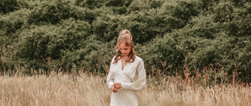 a woman in a white dress standing in a field