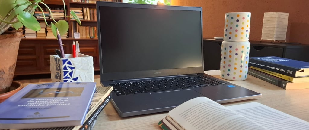 Mesa de trabalho com livros de autoras como Ana Suy, Gayle Rubin e Geni Núñez, ao lado do notebook u