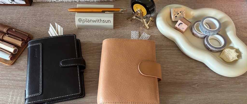 An apricot Moterm pocket planner and a tan Filofax planner on a desk with fountain pens and stamps.