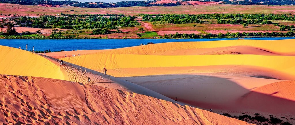 Wide landscape shot of Sand Dunes in Mui Ne Vietnam at sunrise with tiny tourists walking on t