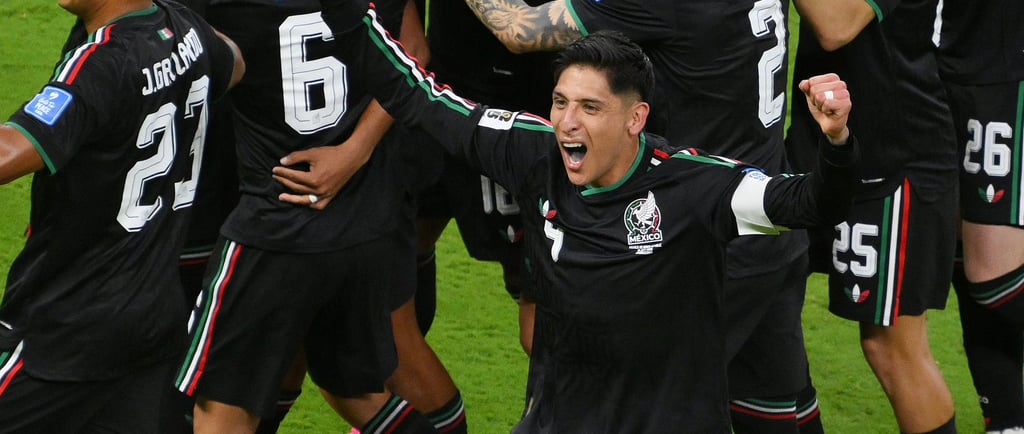 Mexico national football team players celebrating a goal on the field in black jerseys.