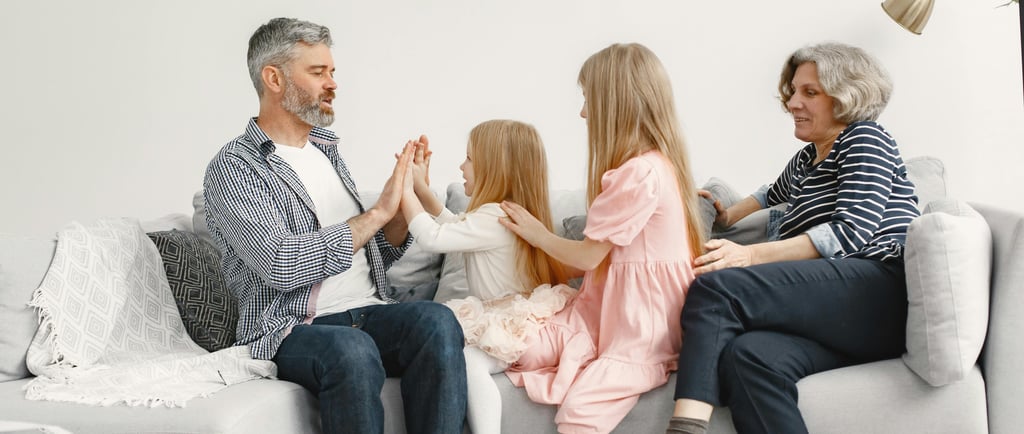 A family sitting on a couch playing games and bonding together in a bright living room.