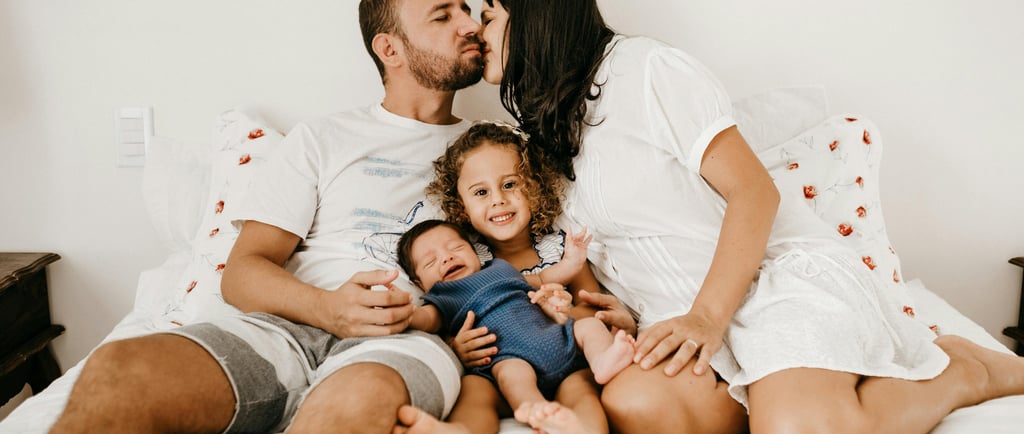 A happy family with a newborn baby and young daughter with happy parents