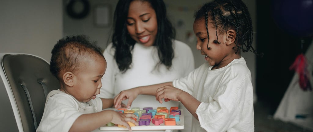 A mother and two young children play with a colorful wooden alphabet puzzle at home.