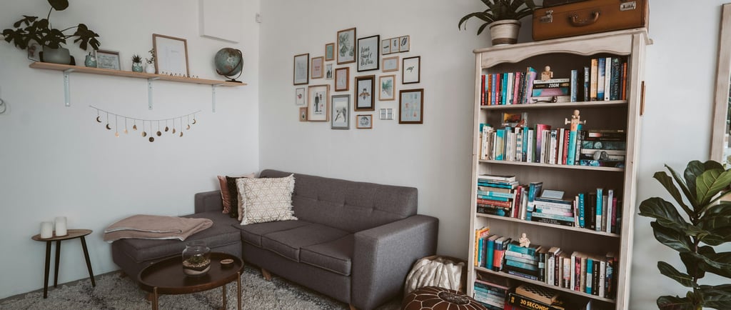 a living room with a couch and a chair and a mini library