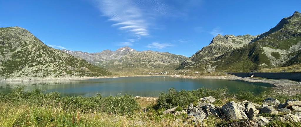 Blick auf einen malerischen Alpensee und die Berge unter strahlend blauem Himmel.