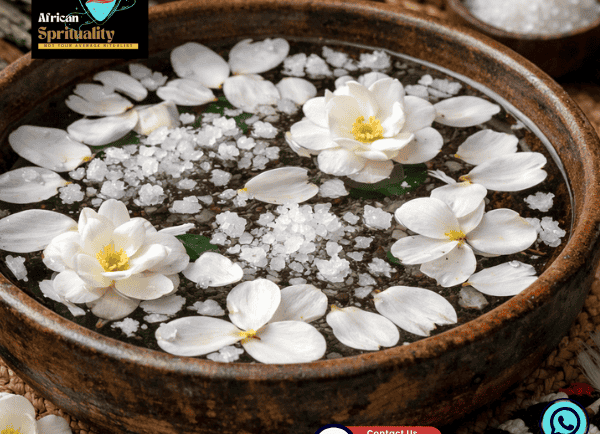 White flowers and ritual salt crystals floating in a ceremonial clay bowl for African spiritual cleansing.