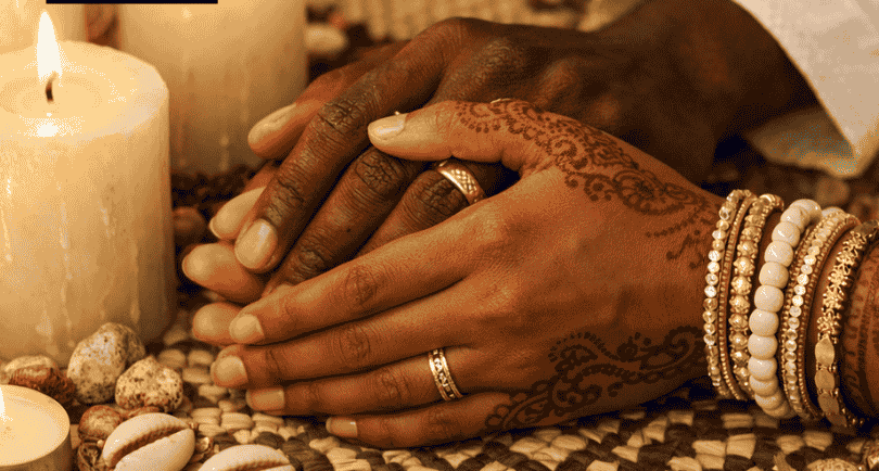 Traditional African spiritual wedding ceremony with joined hands, henna art, and sacred candles.