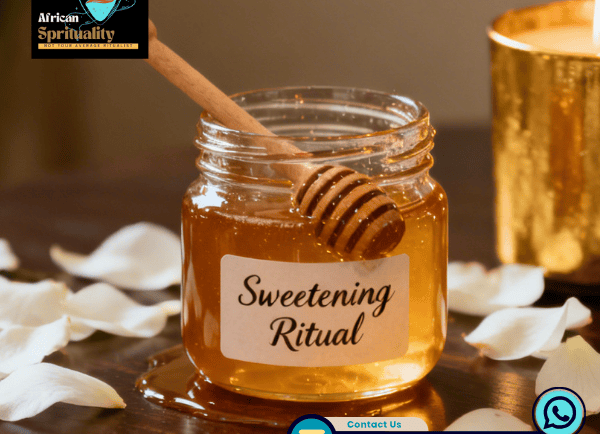 A glass jar of organic honey for a sweetening ritual surrounded by white rose petals and a candle.
