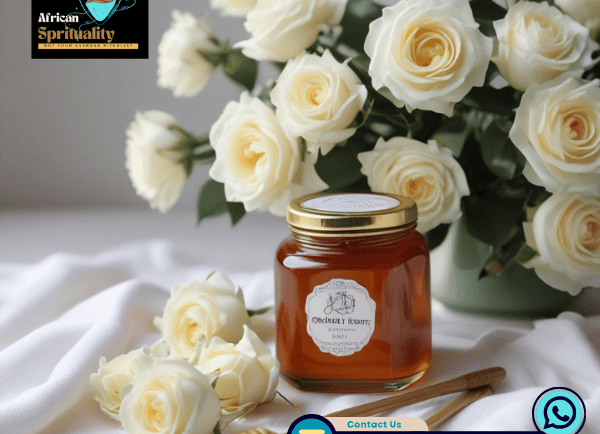 Natural honey jar with white roses and wooden dippers on a soft cloth background.