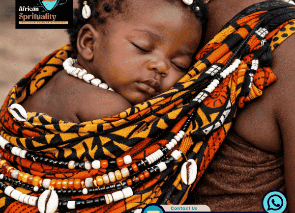 An African baby sleeping in a traditional patterned baby carrier with cowrie shell jewelry and beads.