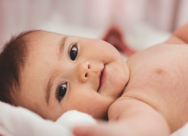 a baby laying and smiling.