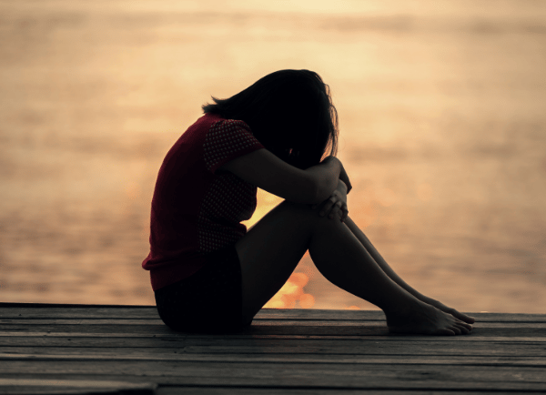 a sad girl sitting on near sea