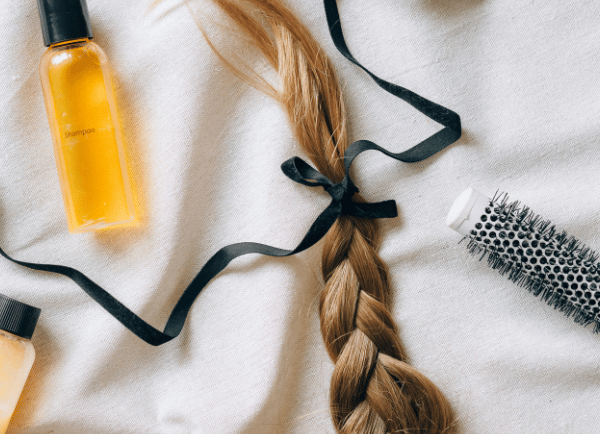 a bottle a brush and a braid of womens hair