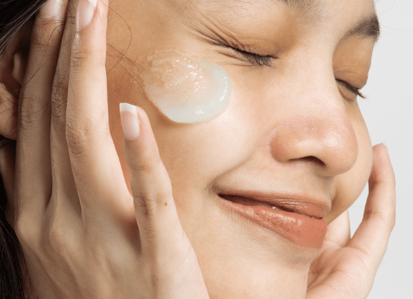 a girl smiling and moisturize is on her face 