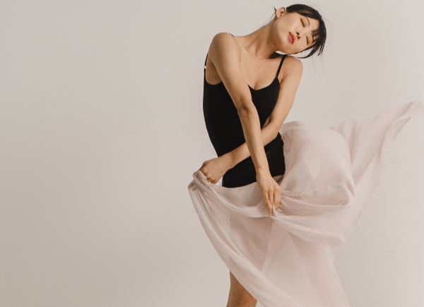 a girl in black top holding pink skirt