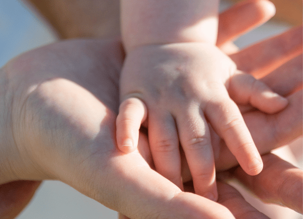 parents holding baby's hand