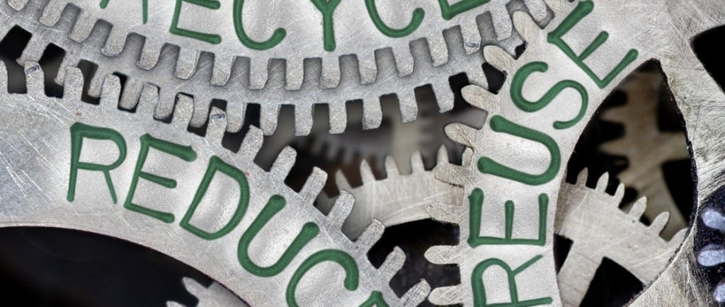 Metal gears with "Reduce," "Reuse," and "Recycle" in green, symbolizing sustainability.