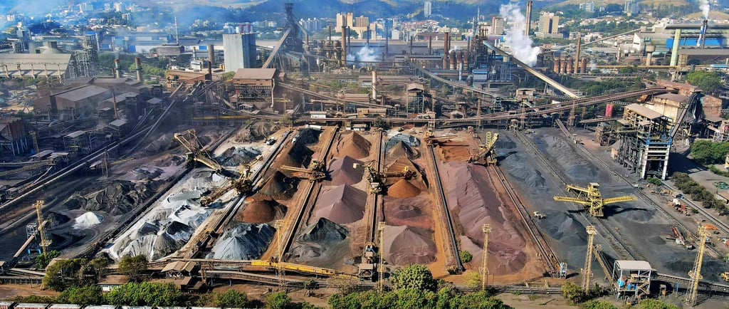 A large-scale industrial mining site with piles of raw minerals, heavy machinery, and conveyor syste