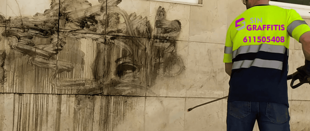 Profesional de Sin Graffitis eliminando graffiti de una fachada con equipo especializado