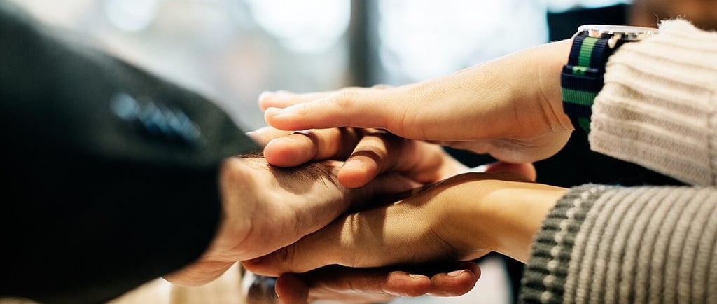 A diverse group of business colleagues stacking their hands together. Photo Credit: Rawpixel Ltd.