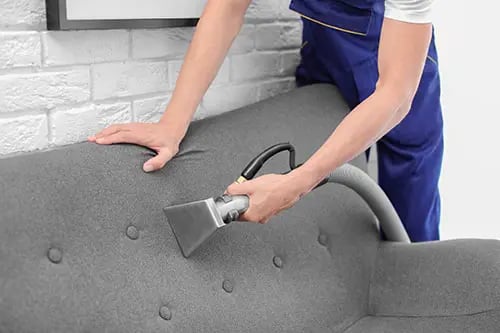 a person cleaning a couch with a vacuum