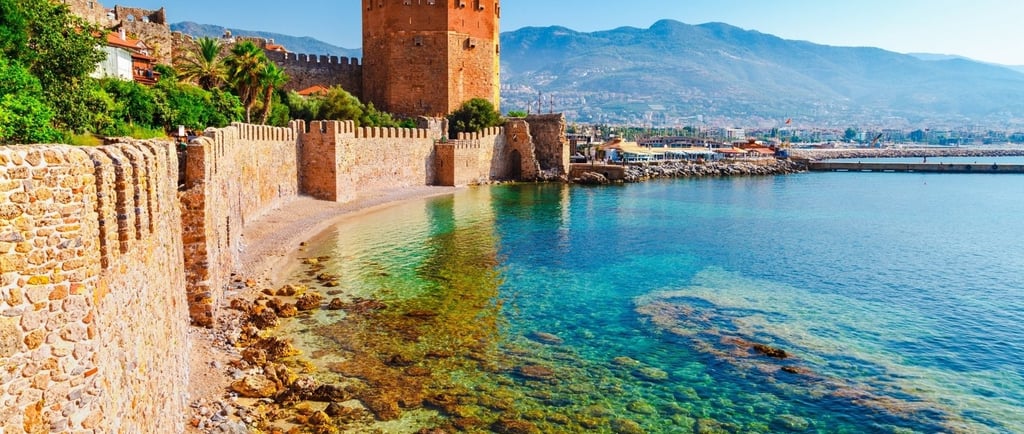 Vista do mar ao lado da cidade murada de Antália, com muralhas históricas à beira da água