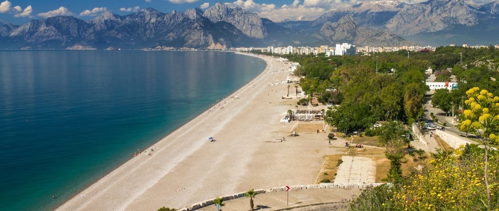 Praia de Koyallti em Antália, com montanhas ao fundo e o mar à frente