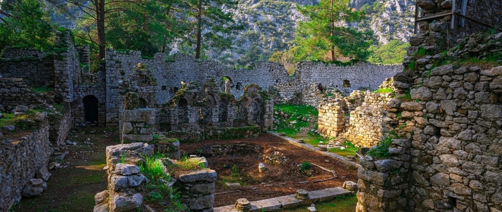 Ruínas de Ólympos em Antália, com vestígios antigos cercados por natureza e céu azul ao fundo